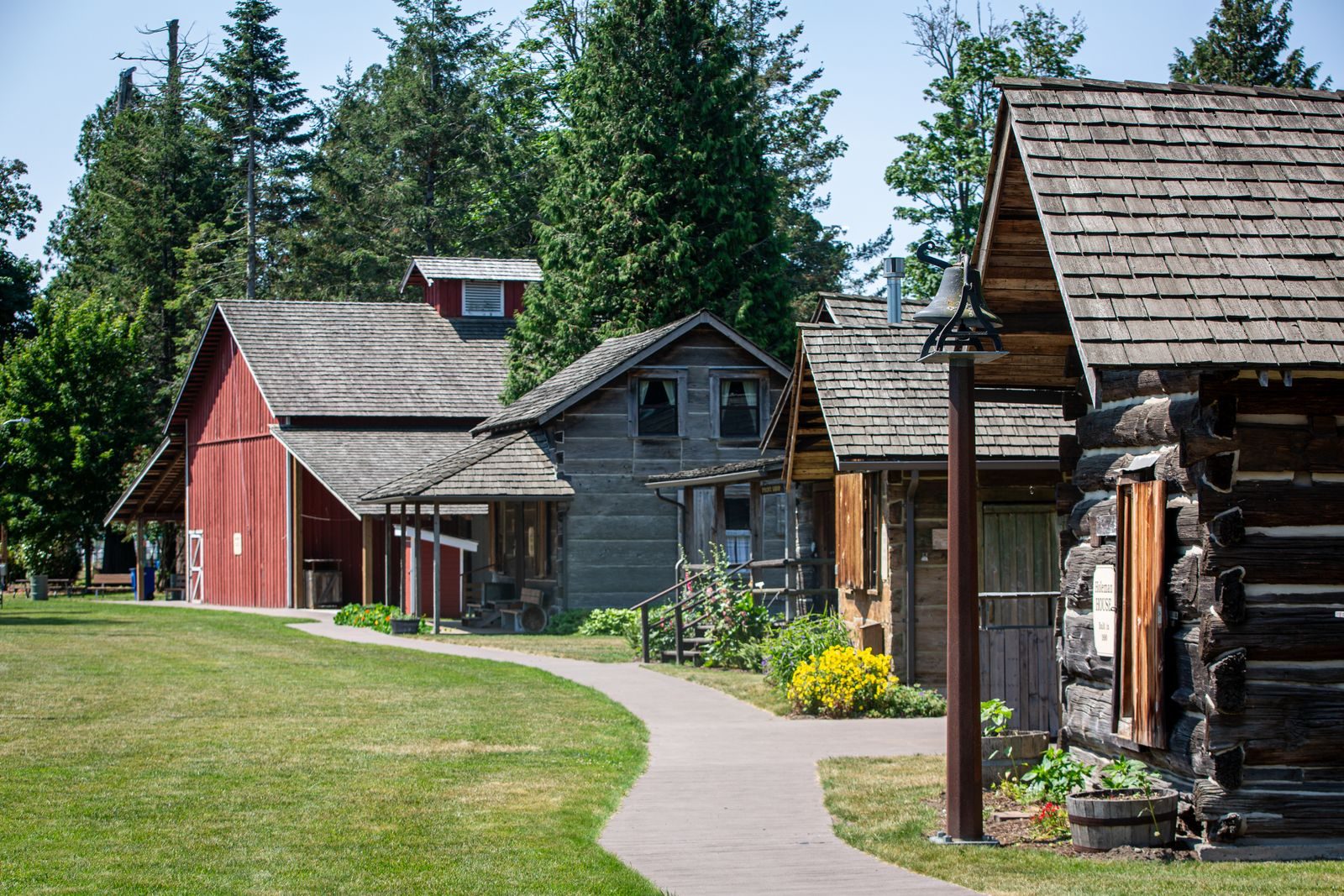 A scenic view of rustic wooden barns and cabins surrounded by lush greenery.